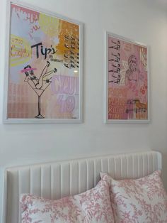 two framed pictures hang on the wall above a bed with pink and white pillows,