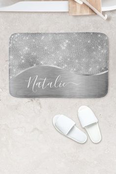 a bath mat with the name natalie on it and two slippers next to it