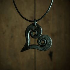 a metal pendant with two spirals hanging on a leather cord