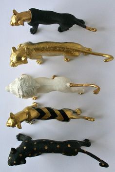 five different animal figurines in gold, black and white on a white background