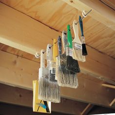 several paint brushes are hanging from the ceiling