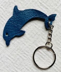 a dolphin keychain is shown on a white towel with a blue fish in the background