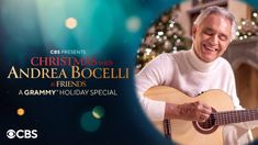 an older man is playing the guitar in front of a christmas tree with lights on it