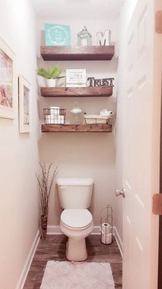 a white toilet sitting inside of a bathroom next to a wooden shelf filled with items