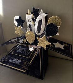 a black and gold 50th birthday card with balloons, stars and confetti on it