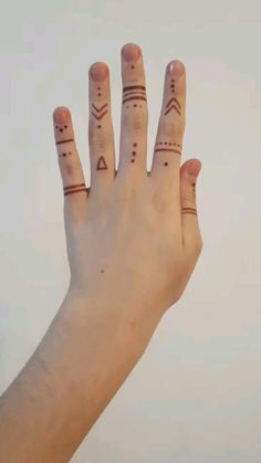 a person's hand with two small tattoos on their fingers and thumbnails