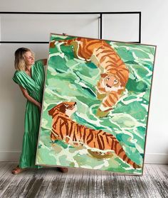 a woman standing in front of a large painting with two tigers swimming on the water