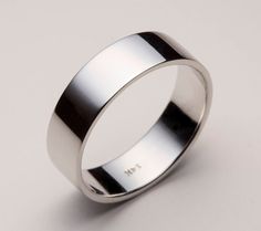 a white gold wedding ring on a plain surface with the word love engraved in it