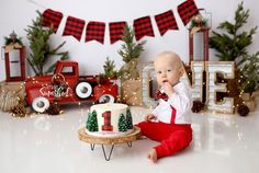 a baby sitting on the floor in front of a christmas cake and decorations for his first birthday