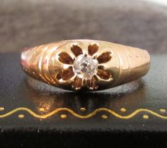 a gold ring with a diamond in the center on top of a black box,