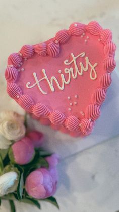 a pink heart shaped cake with the word susten on it next to some flowers