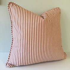 a red and white striped pillow sitting on top of a white table next to a lamp