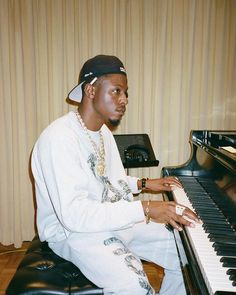 a young man sitting at a piano in front of a wall with curtains on it