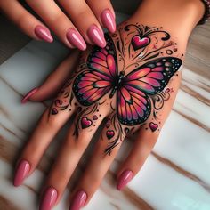 a woman's hand with pink and black nail polishes holding a butterfly tattoo