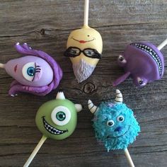 six cake pops with monsters on them sitting next to each other in front of a wooden table