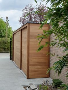 a large wooden shed sitting next to a brick wall in the middle of a garden