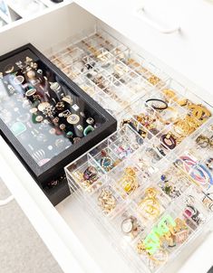 a drawer filled with lots of jewelry on top of a white table