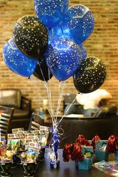 blue and black balloons are in the air on a table with other items around it