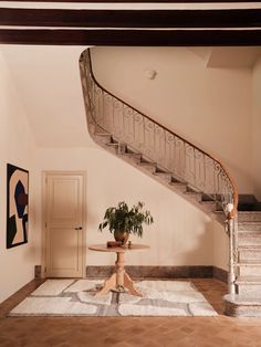 a plant is sitting on a table in the middle of a room next to a stair case