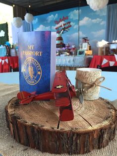 a red plane is sitting on top of a piece of wood in front of a passport