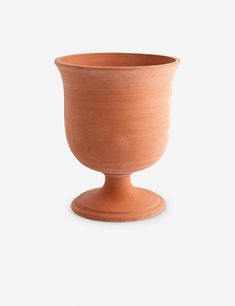 a clay cup sitting on top of a wooden stand