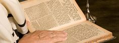 an old man is reading a book with his hands on top of the open book