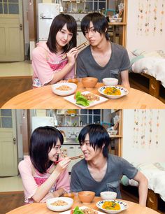 two people sitting at a table with bowls of food and chopsticks in front of them