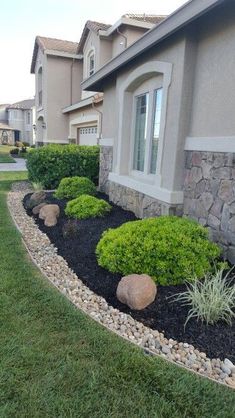 a house with some rocks and plants in the front yard, along with other houses