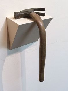 an old hammer stuck into the side of a wall with a piece of wood sticking out of it