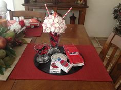 a table topped with a vase filled with flowers and candies on top of a red place mat