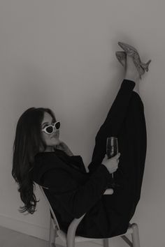 a woman sitting in a chair holding a wine glass and looking up at the ceiling