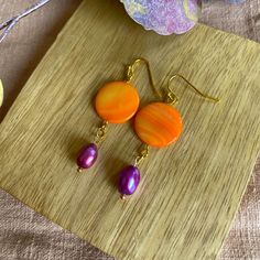 Orange Purple is a pair of handmade pearl earrings. The name speaks for itself with the two colors used: orange and pink/purple. These earrings give every outfit a pop of color and complete every outfit. The pendant made of various materials hangs from the gold-colored metal ear hook. The top one, the flat circle, is made of orange painted mother-of-pearl/shell. Below hangs a pink / purple freshwater pearl. Because the earrings are made with beads that I had in my collection for 10 years, I can't get here again. So you know for sure that you have an (almost) unique pair! There will be several color combinations of this model earring. Because these earrings are made with natural materials, each earring is different. The patterns in the shell, the shapes of the pearls, etc. are different per Purple Pearl Earrings Gift, Purple Pearl Earrings As Gift, Purple Pearl Earrings For Gift, Purple Pearl Earrings For Pierced Ears As A Gift, Vibrant Orange Drop Earrings, Handmade Purple Dangle Pearl Earrings, Orange Round Bead Earrings For Gifts, Purple Dangle Pearl Earrings As Gift, Purple Round Pearl Earrings For Gift