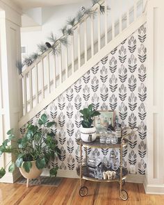 there is a table with plants on it in front of the bannister and stairs