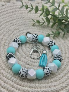 a bracelet with blue and white beads is sitting on a table next to a plant