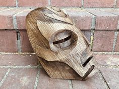 a wooden mask sitting on top of a brick floor