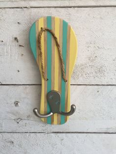 a hook on the side of a wall with a striped board and rope hanging from it