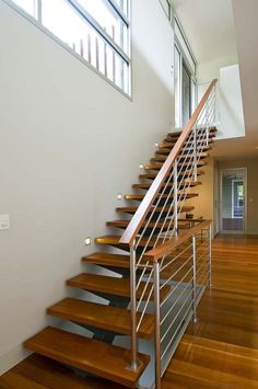 there is a stair case in the middle of this room with wood floors and metal handrails