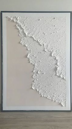 an abstract painting with white paint on the wall and wood flooring in front of it