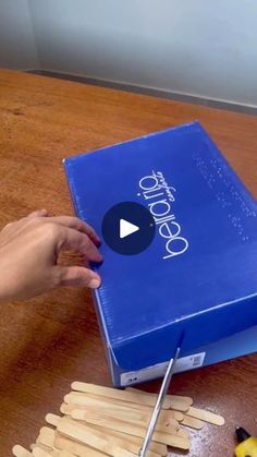 a person cutting popsicle sticks out of a blue box