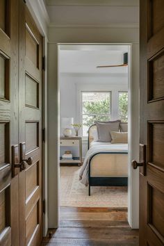 an open door leading to a bedroom with a bed in the middle and two nightstands on either side