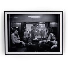 black and white photograph of two people sitting on a train