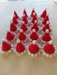 a group of knitted santa hats sitting on top of a white bed covered in pom poms