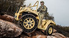 a man riding on the back of a yellow four - wheeled vehicle down a rocky hillside