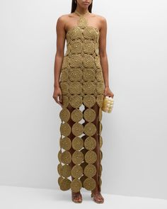 a woman standing in front of a white wall wearing a gold dress with circles on it