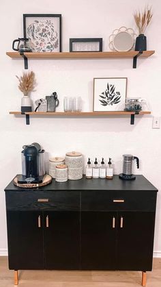 a black cabinet with some shelves above it and coffee cups on top of the cabinets