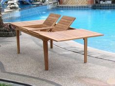 two wooden chairs sitting on top of a table next to a pool