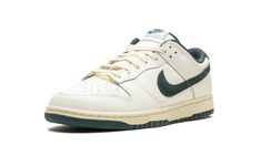 The Nike Dunk Low "Athletic Department - Deep Jungle" is a colorway of the retro basketball sneaker with a vintage college sports aesthetic.  The upper features a Sail leather construction with a Deep Jungle-colored suede Swoosh that matches the appearance of the heel tab with “Nike” embroidery.  Classic “Nike” detailing can be seen on the tongue.  More Deep Jungle accenting includes a green lining, and green rubber outsole underneath the rubber midsole.  A special “Nike Athletic Department” log