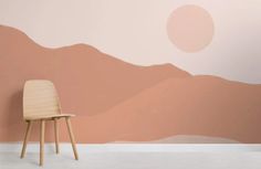 a chair sitting in front of a wall with mountains painted on it