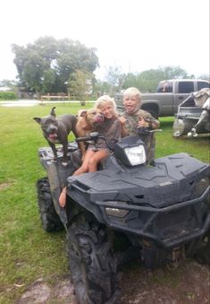 two kids and their dog riding on an atv