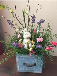 a blue box with flowers and a stuffed animal in it on a table next to a wall